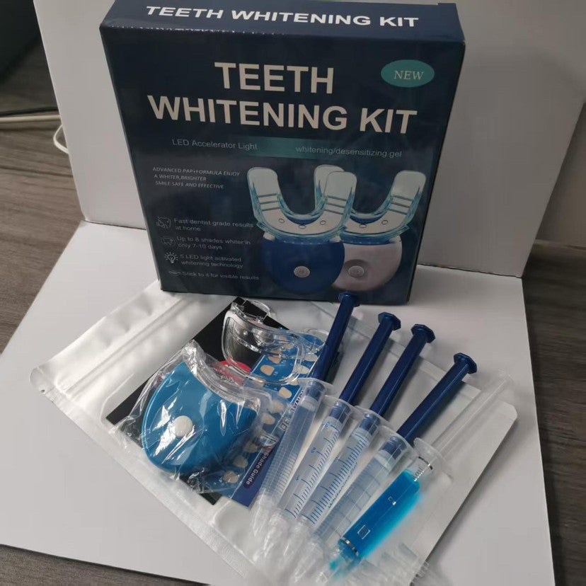 Teeth whitening kit with its blue retail box and included accessories laid out on a white surface, including a blue U-shaped mouthpiece, syringes with gel, and a small accessory pouch.